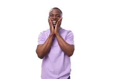 Genç, mutlu, sevimli, efemine tişörtlü Afrikalı adam beyaz arka planda gülüyor..