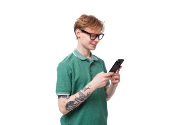 Gözlüklü, kızıl saçlı, genç, sakin adam telefona bir mesaj yazıyor..