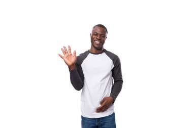 Genç Amerikalı sıradan giyinmiş, beyaz arka planda dişleri olan, geniş gülümsemeli bir adam..