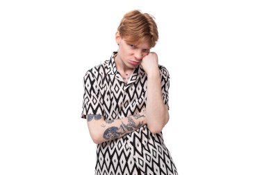 Kırmızı saçlı, kısa kollu gömlekli, beyaz arka planda poz veren genç, yorgun ve üzgün bir adam..