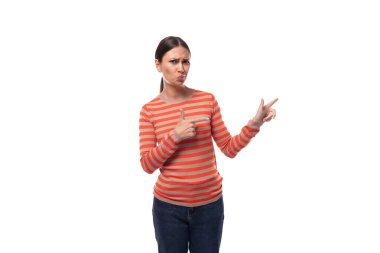 Çizgili turuncu bluz ve kot pantolon giymiş genç, zeki, zayıf esmer kadın reklam alanına elini uzatıyor..