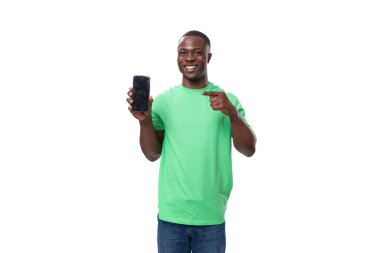 Genç, şaşkın, yeşil tişörtlü Amerikalı adam akıllı telefon ve model gösteriyor..
