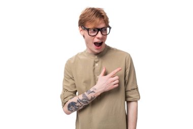 Kolunda dövme olan genç, duygusal yakışıklı bir adam haki rengi bir gömlek giyiyor..