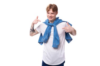 Kollarında dövmesi olan altın sarısı kızıl saçlı beyaz bir adam mavi bir gömlek giyiyor..