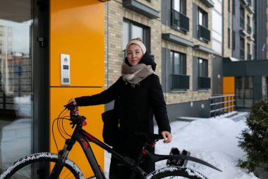 Sarışın, sırıtan hoş bir kadın eşarp takmış kışlık ceket giyiyor..