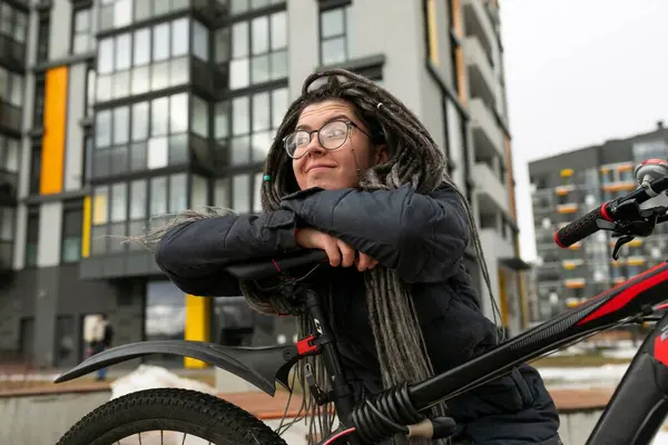 Bisiklet kiralama konsepti. Rastalı genç Avrupalı bir kadın tatilini bisiklet sürerek geçiriyor..