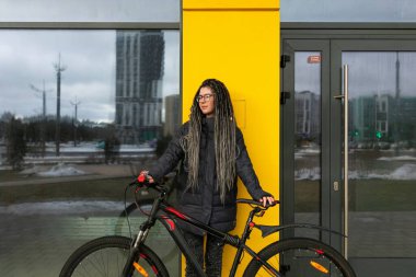 Şehir ortamında saç stili ve bisikleti olan hoş bir genç kadın..