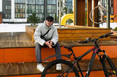 Sonbahar elbiseli genç bir adam bisiklet sürdükten sonra dinlenmek için oturdu..