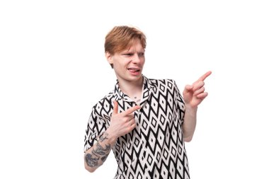 Kısa kollu beyaz gömlekli genç, kızıl saçlı adam elini yana doğru gösteriyor..