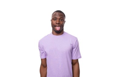 Kısa saçlı, eflatun tişörtlü, neşeli Afrikalı genç adam yüzünü buruşturuyor..