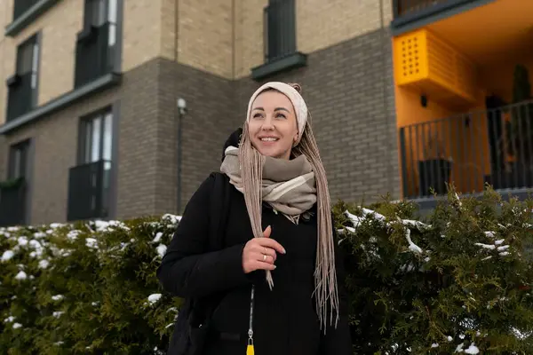 Kış mevsiminde eşarp takmış siyah bir ceket giymiş bakımlı genç bir kadın kışın şehirde dolaşıyor..