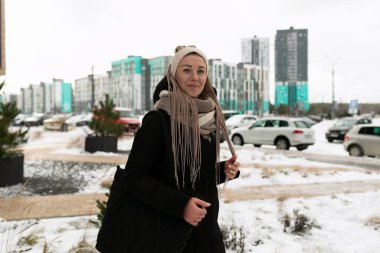 Siyah, uzun kış ceketi giyen, sarı saçlı, gülümseyen tatlı bir kadın..