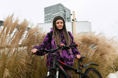 Piercingli ve rastalı hoş genç bir kadın şehirde bisiklet kiralamış..
