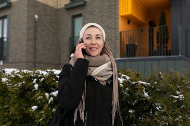 Sarışın, sırıtan hoş bir kadın eşarp takmış kışlık ceket giyiyor..