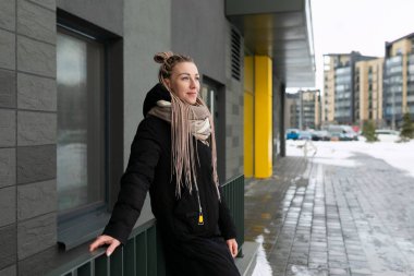 Siyah ceketli, rastalı güzel bir genç kadın şehirde yürüyor..