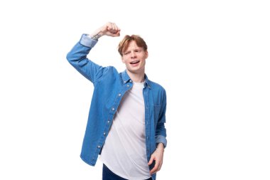 Mavi kot gömlekli genç, kızıl saçlı bir adam aktif olarak el kol hareketi yapıyor. reklam kavramı.