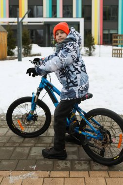 Avrupalı çocuk kışın bahçede bisiklet sürüyor.