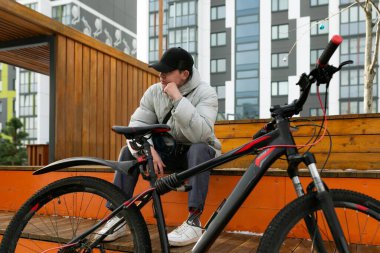 Şapkalı ve ceketli bir adam şehirde bisikletli bir yürüyüşün tadını çıkarır..