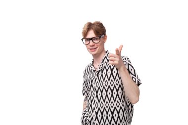 Genç, kızıl saçlı, beyaz gözlüklü, kısa kollu, siyah beyaz gömlekli bir adam..