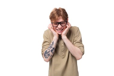 Kolunda dövmesi olan açık kahverengi gömlekli genç, kızıl saçlı Avrupalı bir adam..