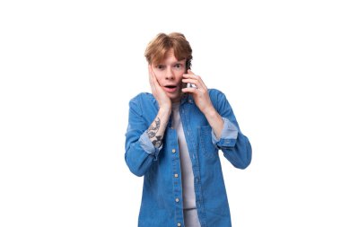 Mavi gömlekli, kızıl saçlı genç bir adam telefonda endişeyle konuşuyor..