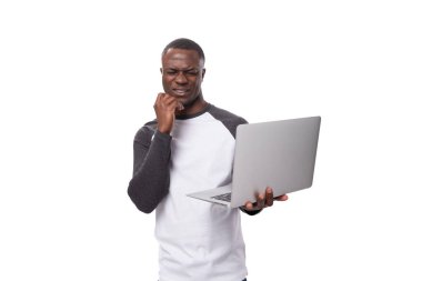 Siyah beyaz kazak giymiş genç bir Amerikalı elinde gri bir dizüstü bilgisayarla beyaz bir arka planda fotokopi çekiyordu..