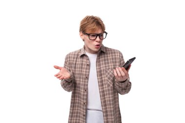 Beyaz saçlı, tişörtlü genç bir adam elinde akıllı bir telefon tutuyor..