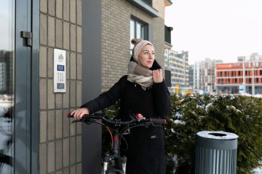 Kışın şehirde bisiklet süren sevimli genç bir kadın..