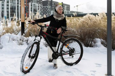 Atletik aktif genç kadın kışın sokakta bisiklet sürüyor..