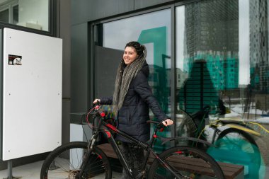 Sokakta çekilen fotoğrafta, genç bir kadın kışın bisikletini yürüyüşe çıkardı..