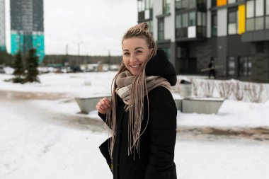 Sarışın, sevimli bir kadın kışın karla birlikte şehirde yürüyor..