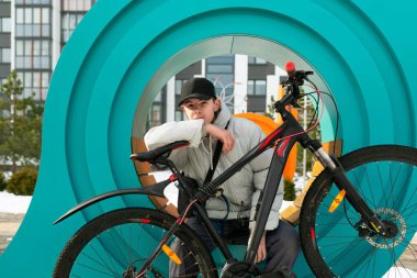 Sonbahar elbiseli genç bir adam bisiklet sürdükten sonra dinlenmek için oturdu..