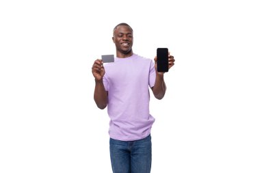 Kısa saçlı, açık mor tişörtlü, elinde kredi kartı ve akıllı telefon olan genç, şık bir Amerikalı..