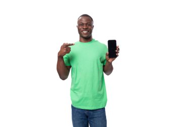 Açık yeşil tişörtlü, kot pantolonlu, akıllı telefonlu yakışıklı Afrikalı bir adam..