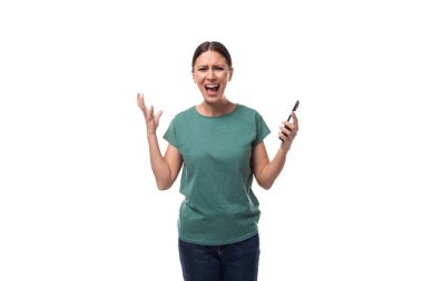 30 yaşında, hayal kırıklığına uğramış, saçları toplanmış esmer kadın yeşil bir tişört ve iktidarsızlıkla bağıran kot pantolon giyiyor..