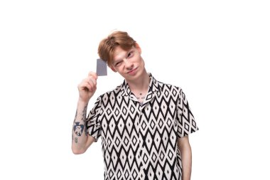 Kırmızımsı altın saçlı beyaz bir adam elinde sahte bir kredi kartı tutuyor..