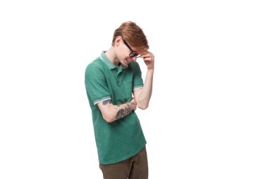 Genç, beyaz, yeşil tişörtlü, kızıl saçlı adamın şüpheleri ve düşünceleri var..