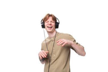 Genç, yakışıklı, kızıl saçlı, büyük kulaklıklarla müzik eşliğinde dans eden öğrenci..