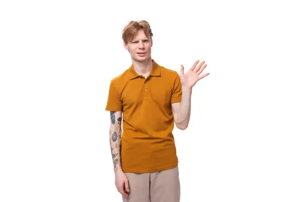 stock image young red-haired guy in a yellow t-shirt waving his hand.