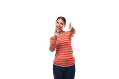 Siyah saçlı, çizgili turuncu ceketli beyaz bir kadın elleriyle hareket ediyor ve dikkat çekiyor..