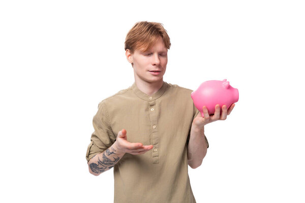 young cute caucasian guy with red hair decides where to spend his savings.