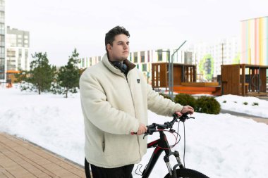 Kışın şehirde bisiklet süren sevimli bir genç adam..