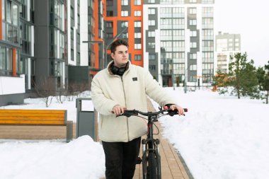 Kışlık ceketli genç bir Avrupalı bisikletini dışarı çıkardı..