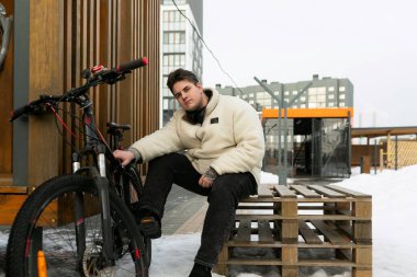 Spor konsepti, genç adam oturuyor ve bisikletli arkadaşını bekliyor..