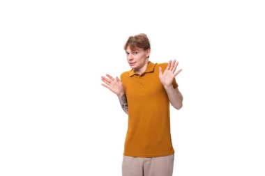 Kızıl saçlı beyaz bir genç stüdyo arka planında sarı bir tişört giyiyor..