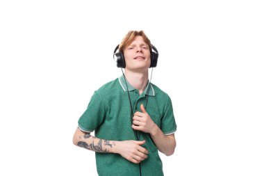 Kırmızı saçlı, yeşil tişörtlü, büyük kulaklıklı genç bir adam dans ediyor ve....