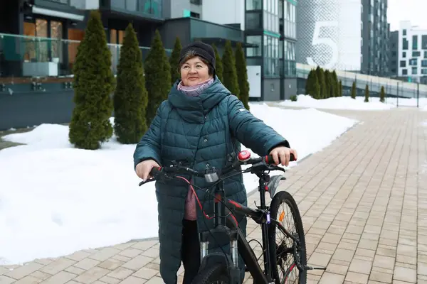 一位老年妇女骑着自行车在城市里转悠 — 图库照片