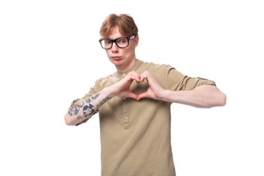 Kolunda dövmesi olan, bej rengi gömlek giyen, Avrupalı genç ve şık bir adam..