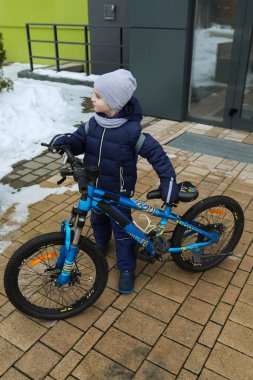 Mutlu beyaz çocuk bisikletini yürüyüşe çıkarıyor..