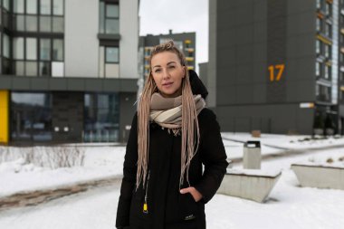 Kışın şehirde yürüyen rastalı hoş bir genç kadın..